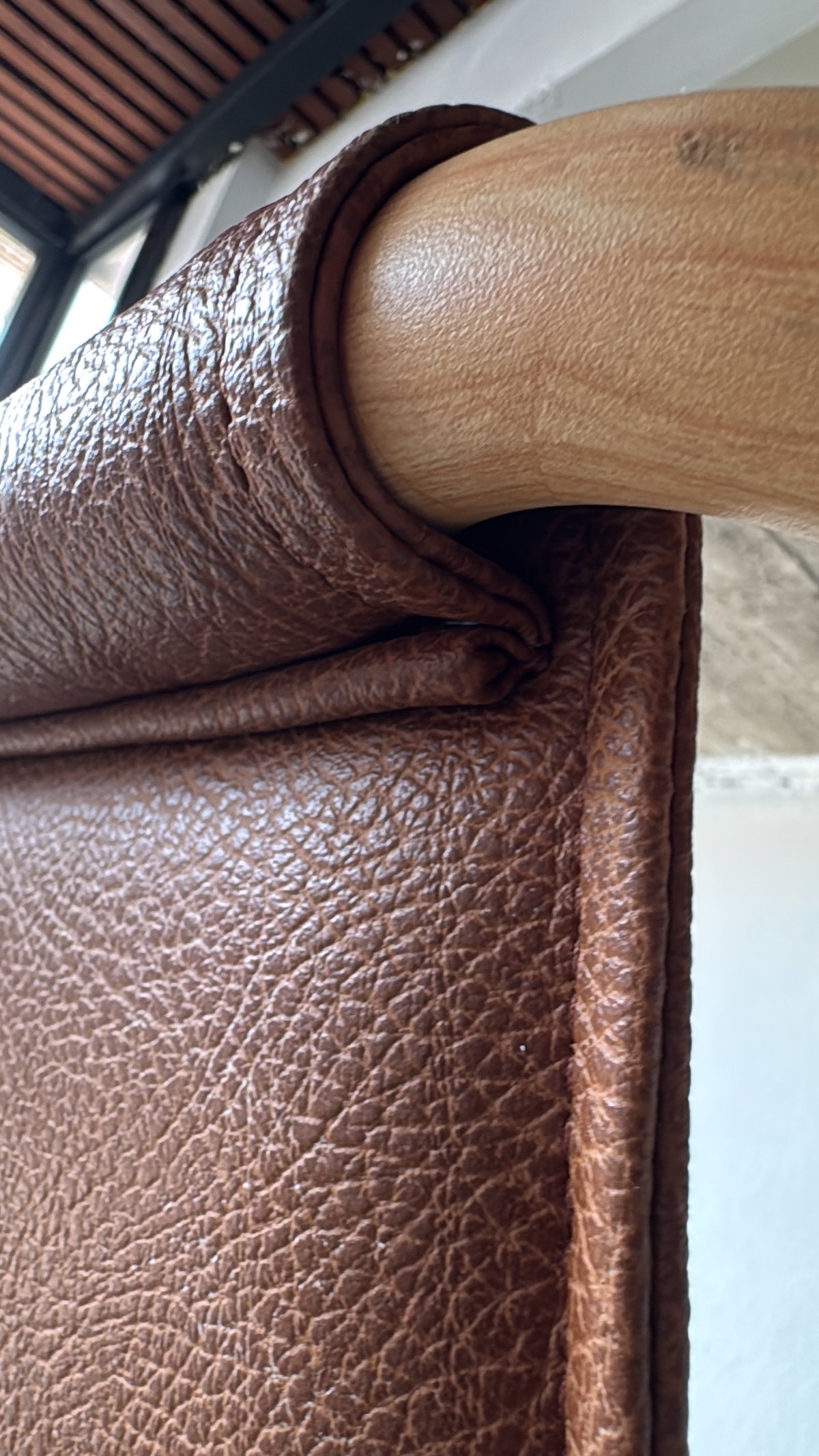 Detalle de sillón de piel con marco de madera y borde enrollado